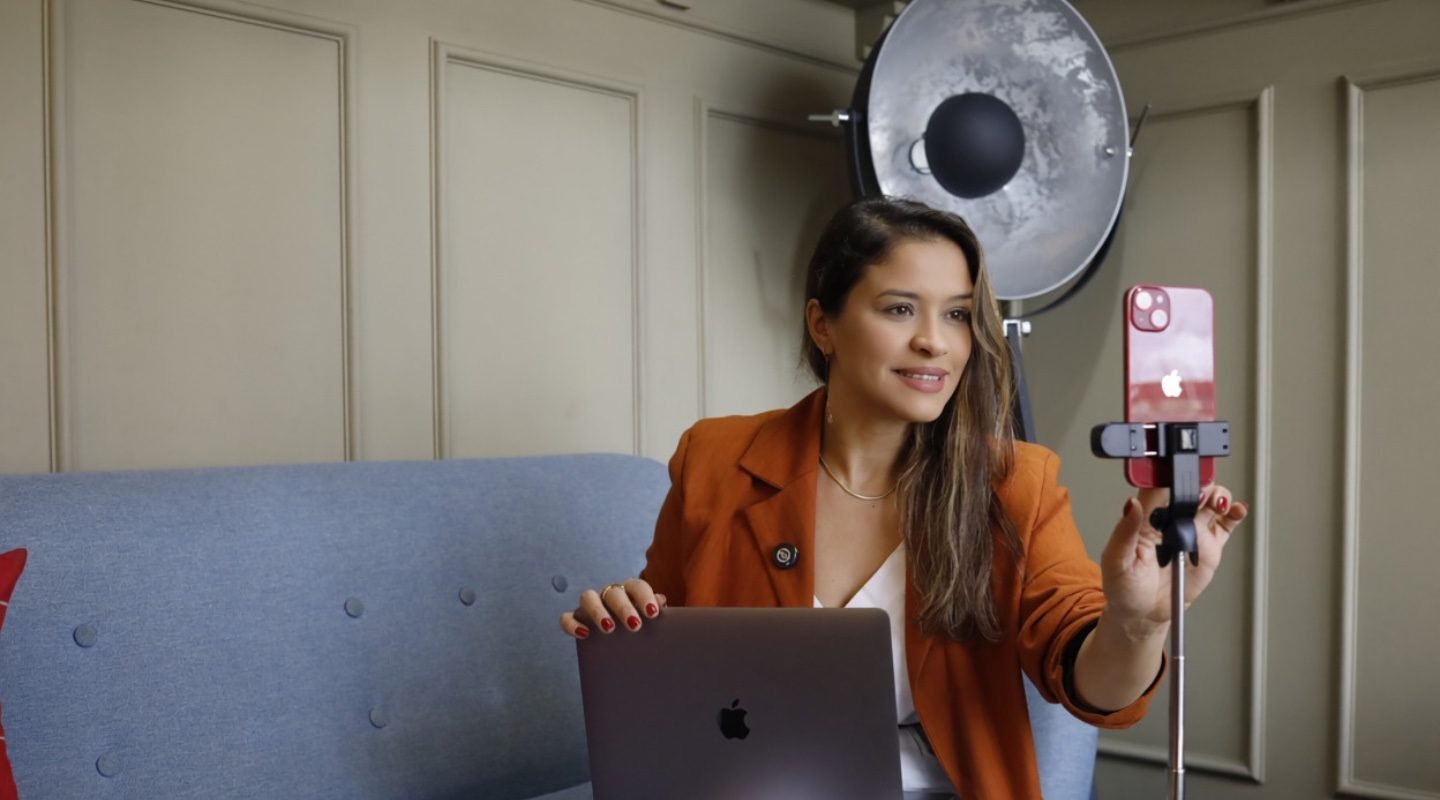 Ingrid gravando um vídeo com o celular no tripé