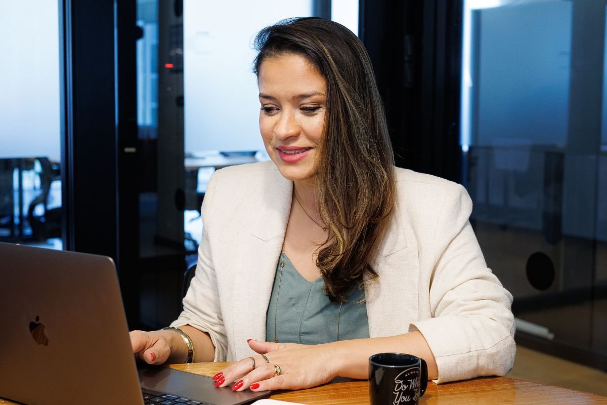 Ingrid de blazer creme, trabalhando no notebook