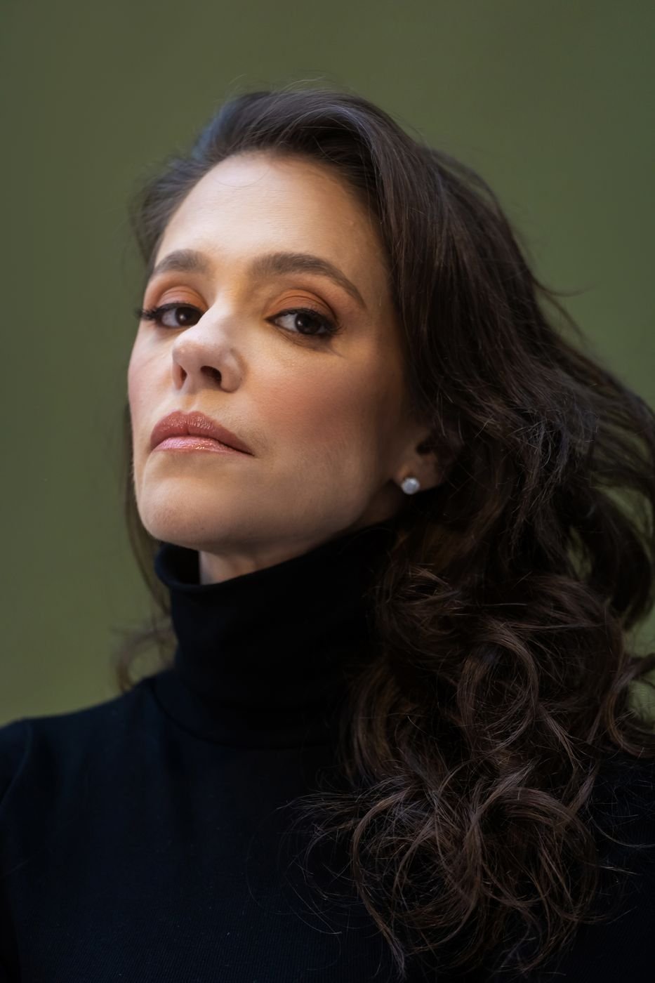 Portfólio da Ingrid: retrato de uma cliente de blusa preta, em fundo verde